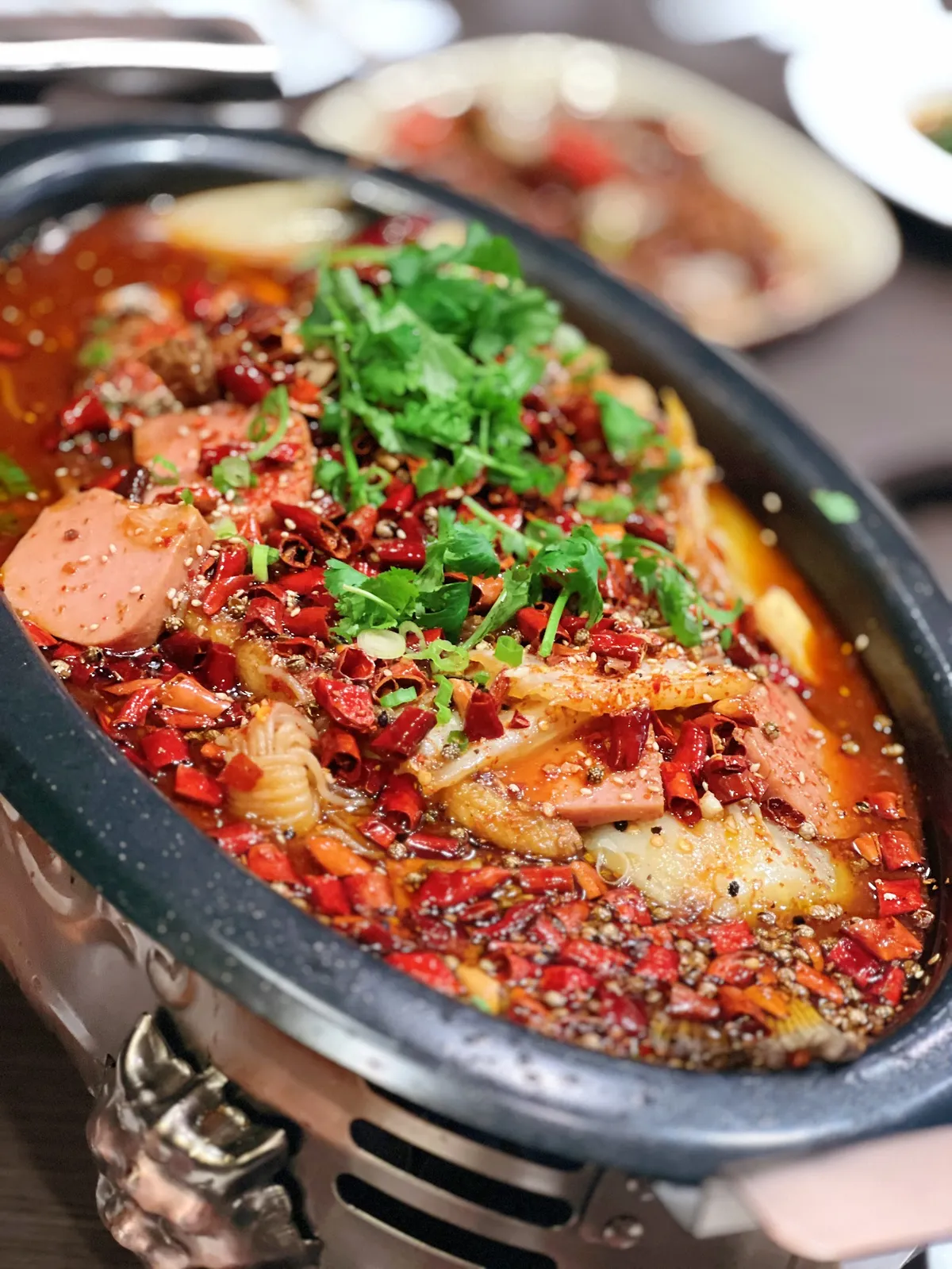Spicy Chinese dish with chili peppers and cilantro in a pot