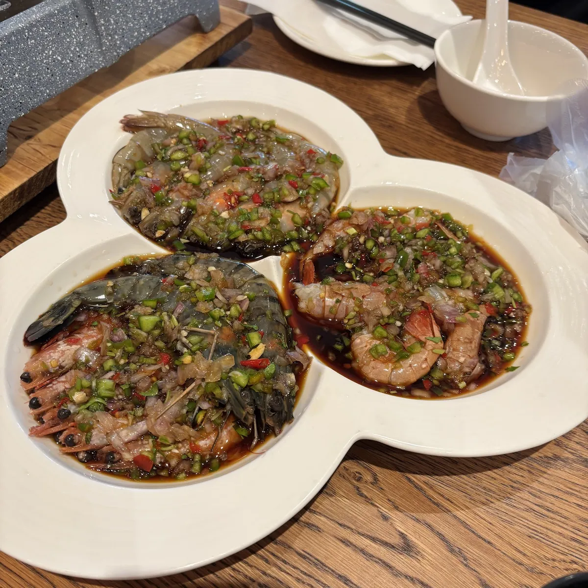 Marinated raw shrimp with chili and herbs on a white plate